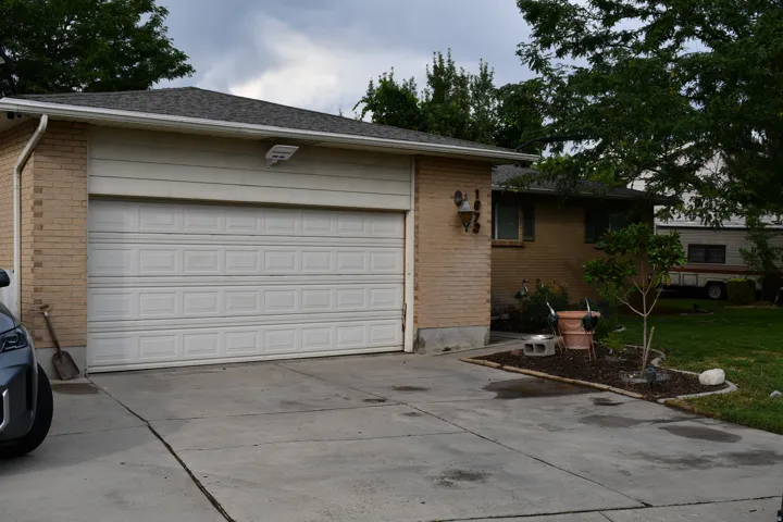 Attached two-car garage with a white panel door, brick exterior, and concrete driveway