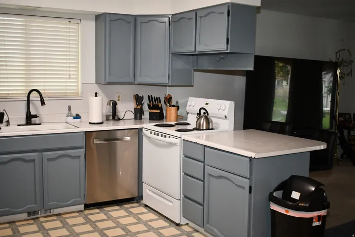 Updated cabinetry with white countertops, a stainless steel dishwasher, and a white electric range