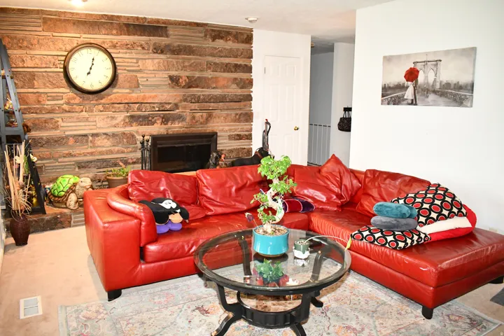 Stone-clad fireplace with hearth, white painted walls, and light-colored carpeting