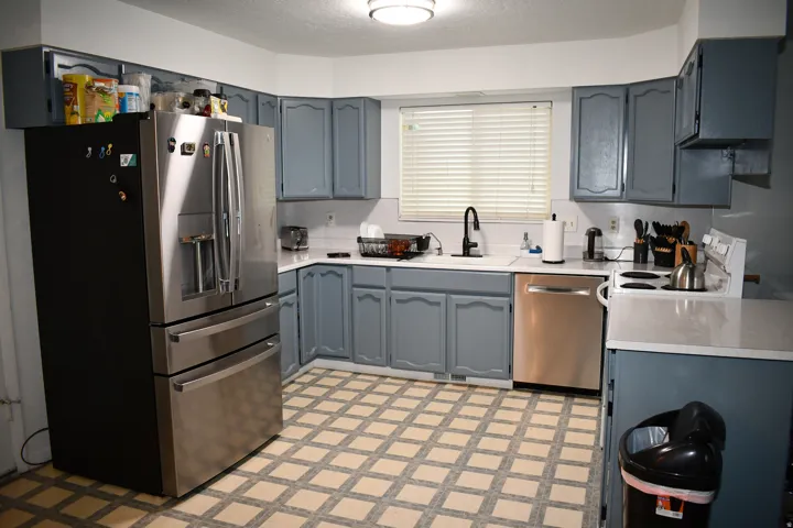 Kitchen featuring blue cabinetry, white countertops, stainless steel appliances, and patterned tile flooring