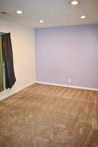 Recessed lighting illuminates the carpeted flooring