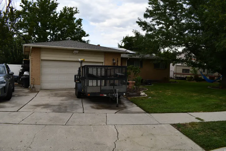 Attached single-car garage with a paneled door, brick exterior accents, and a paved driveway