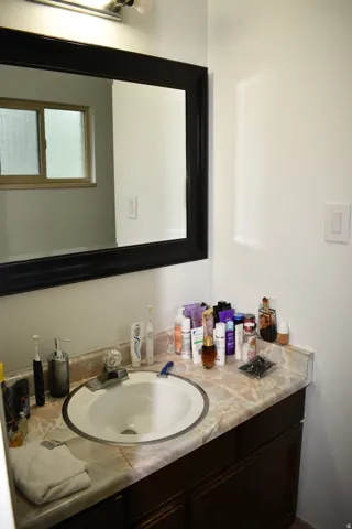 Vanity with a marble-look countertop and an integrated sink, framed mirror, and chrome vanity light fixture