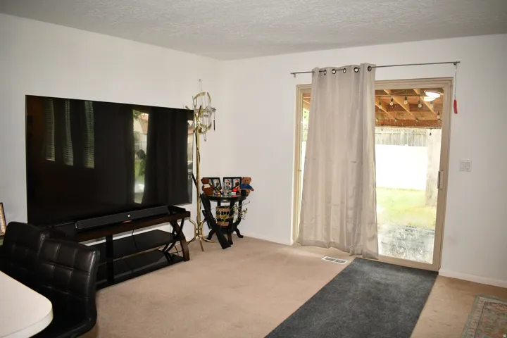 Sliding glass door access to the exterior, with a textured ceiling and neutral wall paint