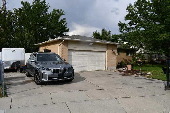 Attached two-car garage with a white panel door, light brick exterior, and a concrete driveway
