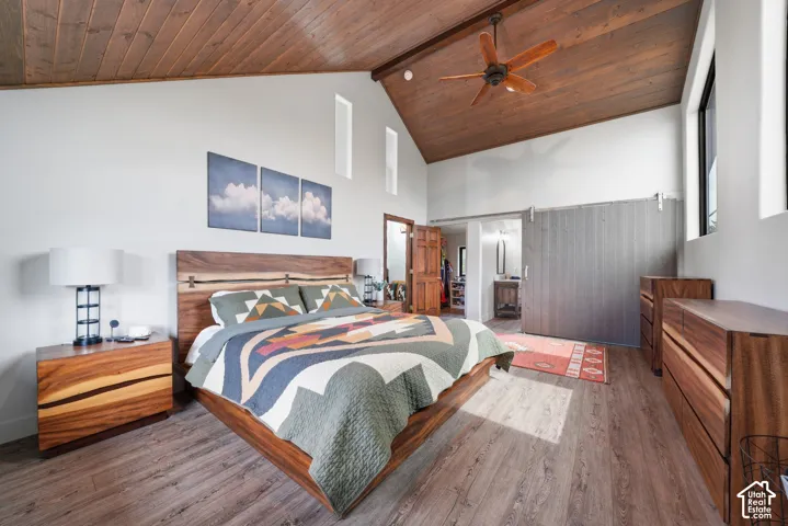 Vaulted wood-plank ceiling with a ceiling fan, wood-finish flooring, high windows, and a sliding barn door