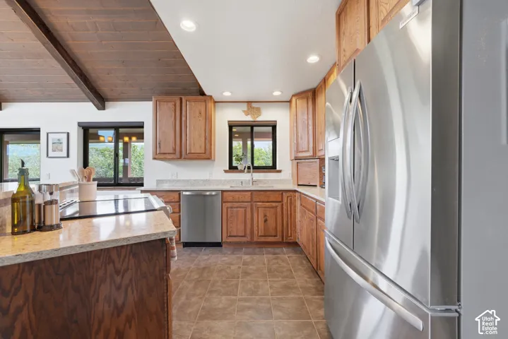 Kitchen featuring wood cabinetry, stainless steel appliances, recessed lighting, and a wood-beamed ceiling