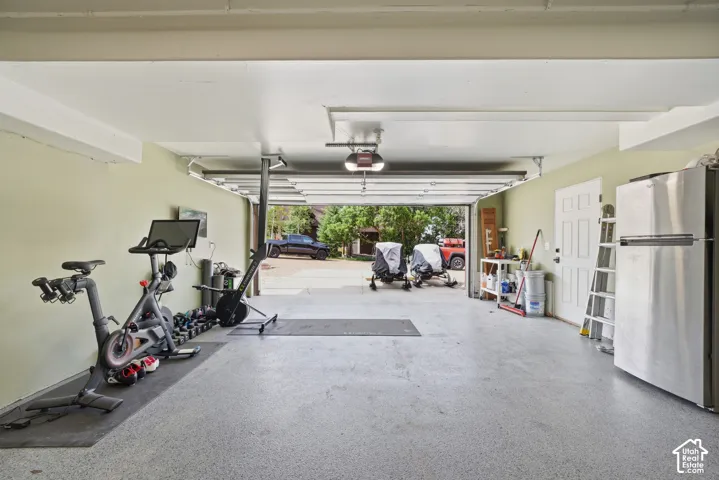 Spacious garage with light-colored walls, exposed ceiling beams, and a light gray epoxy floor