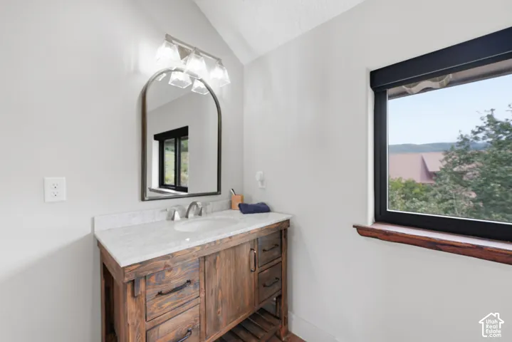 Spa-inspired bathroom vanity featuring a wood-finish cabinet base with multiple drawers and storage, paired with a marble-topped countertop and polished nickel faucet fixtures