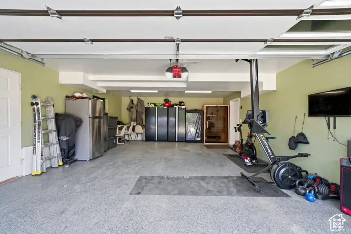 Spacious garage featuring a durable epoxy floor, recessed lighting, and a white paneled door