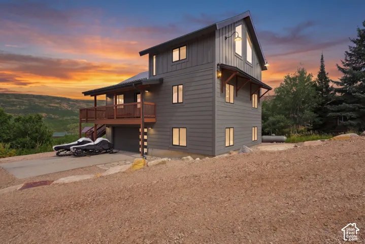 Contemporary exterior with vertical and horizontal siding, multiple windows, a covered balcony, and a garage door