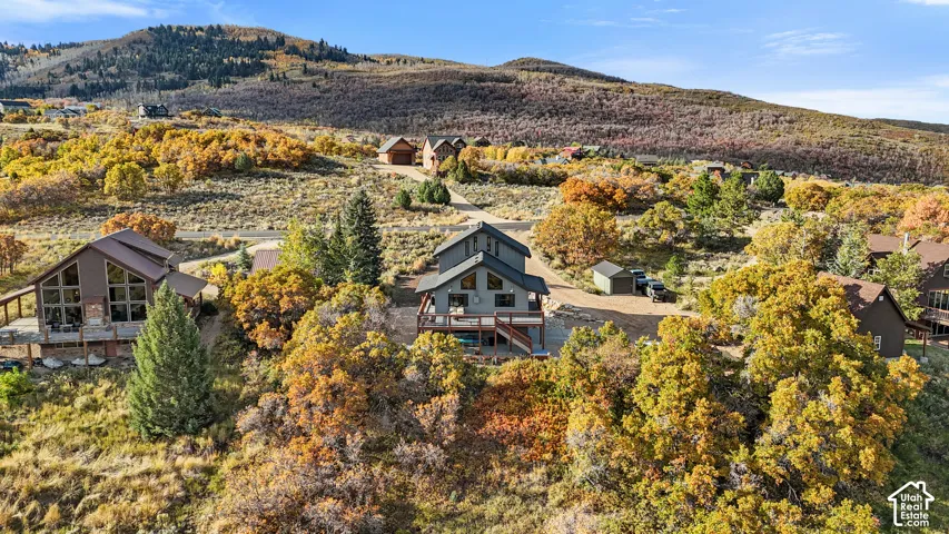 Modern architectural home nestled in a high-elevation setting with expansive mountain vistas, surrounded by mature aspen and evergreen trees displaying golden autumn foliage