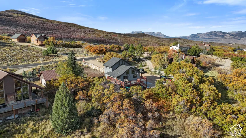 Hillside property with a multi-level structure, a dark grey roof, and a red-toned outdoor deck