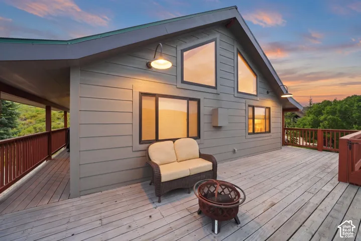 Expansive wood deck with a covered portion, featuring a wood-sided exterior, a pitched roofline, and multiple large windows