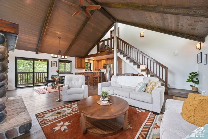 Vaulted wood-paneled ceiling with exposed beams, stone fireplace with a substantial hearth, wood-finish flooring, and a multi-level staircase with wood railings