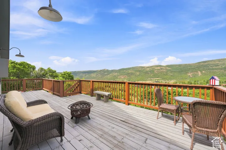 Spacious outdoor deck with wood railing, broad mountain scenery, and an overhead light fixture