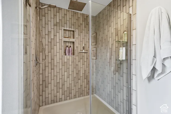 Enclosed shower with full-height vertical tilework, built-in shower niche, and a square rain showerhead
