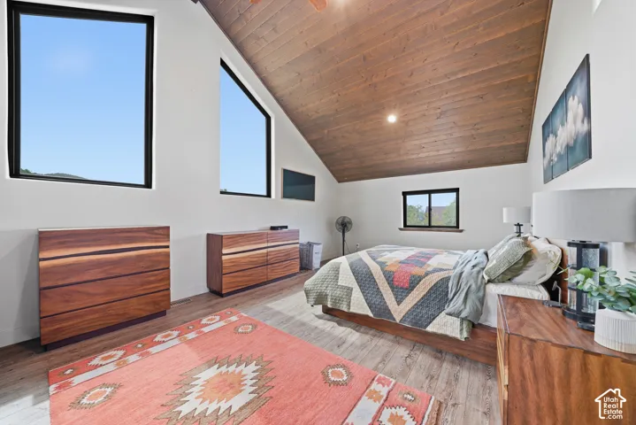 Sloped wood-finish ceiling, large rectangular windows, wood-finish flooring, recessed lighting, and white walls