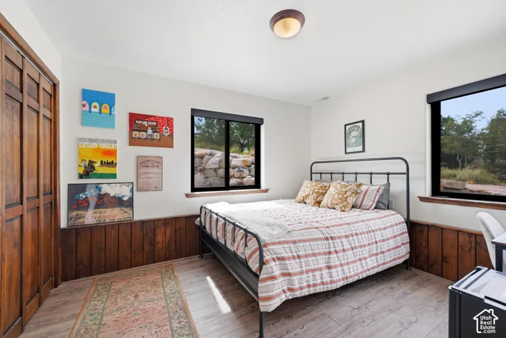Spacious bedroom featuring a metal-frame bed, wood-finish flooring, and wood-paneled walling