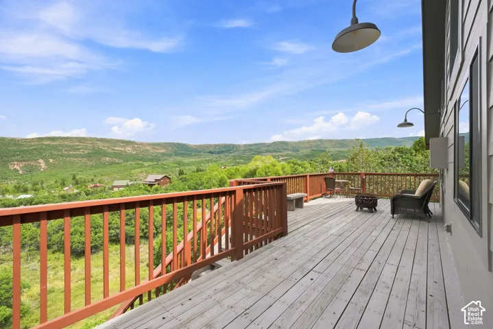 Expansive outdoor deck with wood railing, offering a sweeping mountain and valley backdrop