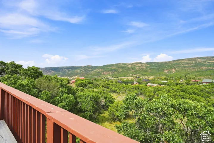 Expansive natural scenery with distant structures, visible from a brown wooden railing