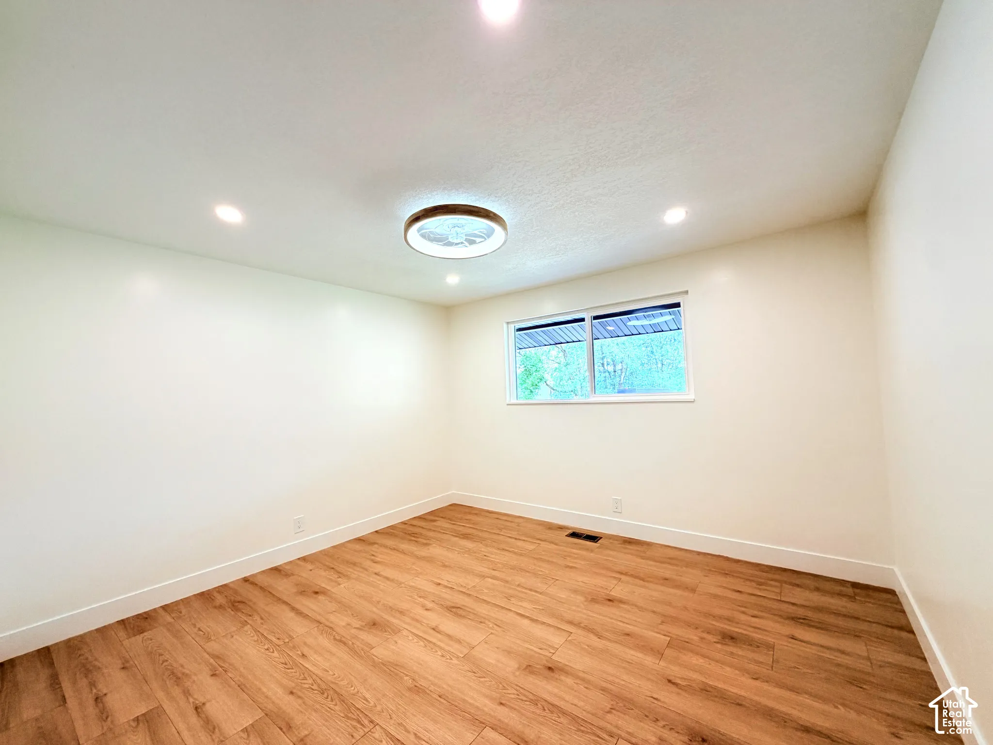 Recessed ceiling lighting, wood-finish flooring, white trim, and a window for natural illumination