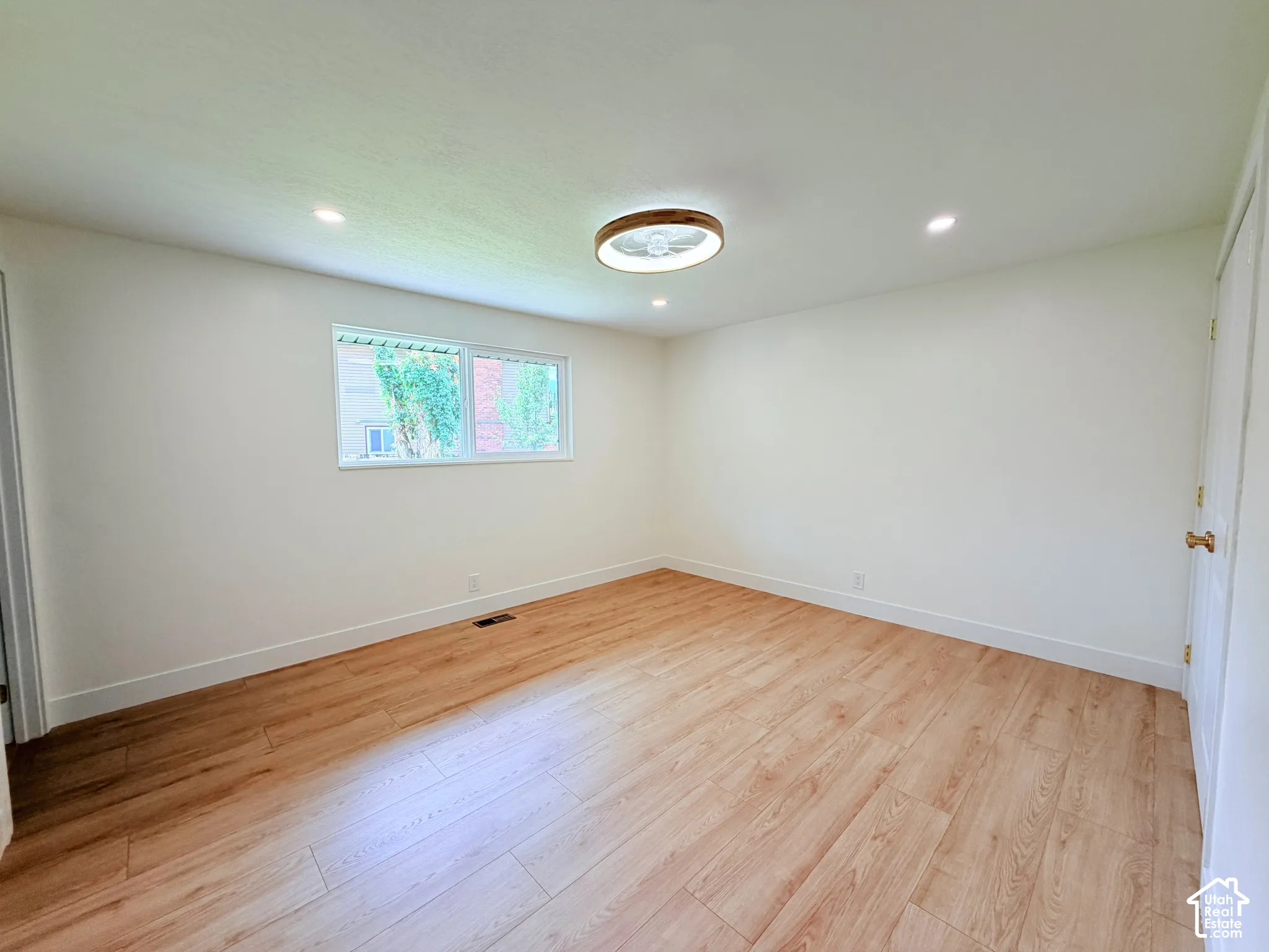 Recessed ceiling lighting, wood-finish flooring, white walls, double-pane window, and a modern ceiling fixture