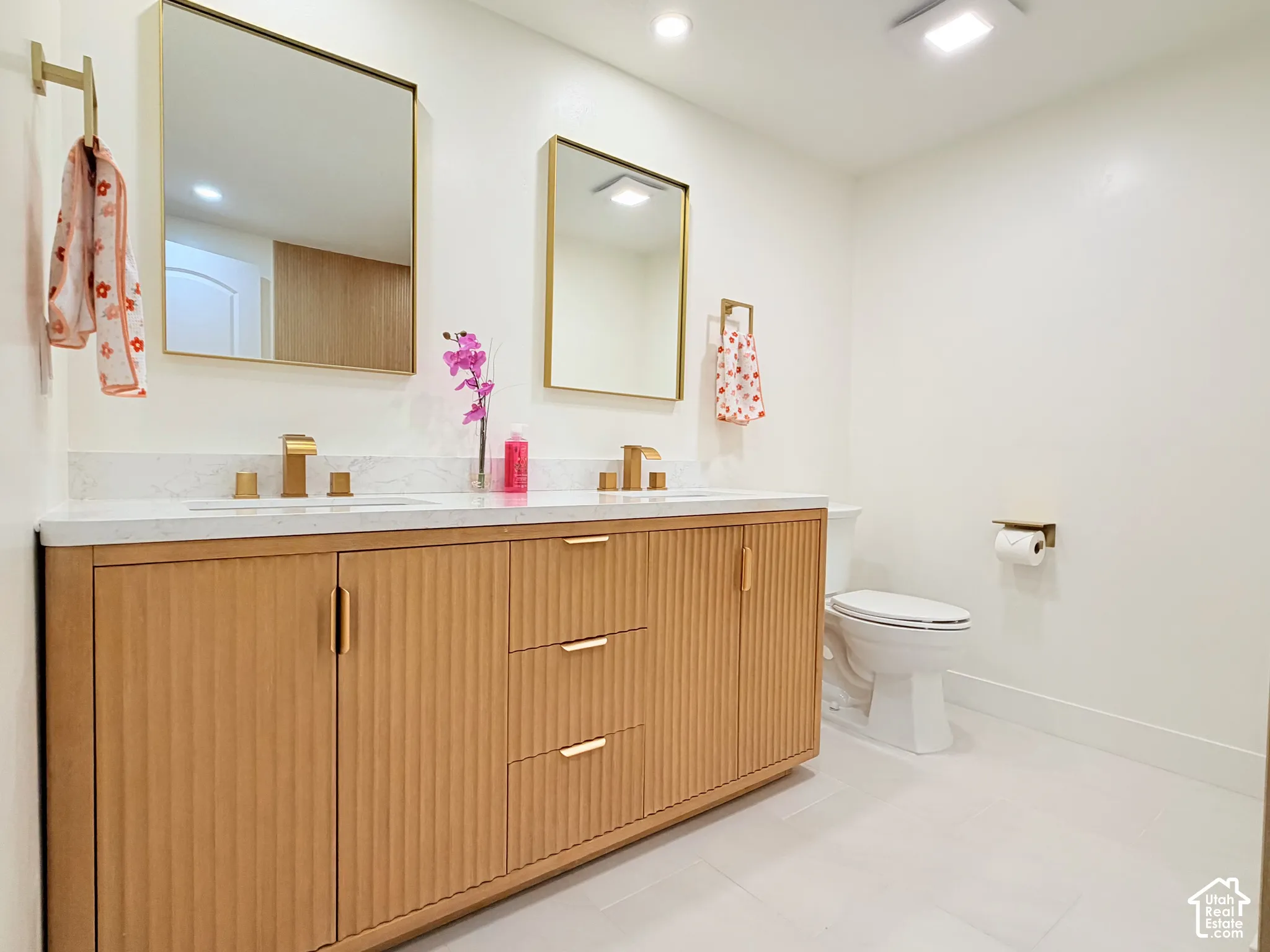 Double vanity with fluted wood cabinetry, dual undermount sinks, and gold-finish faucets
