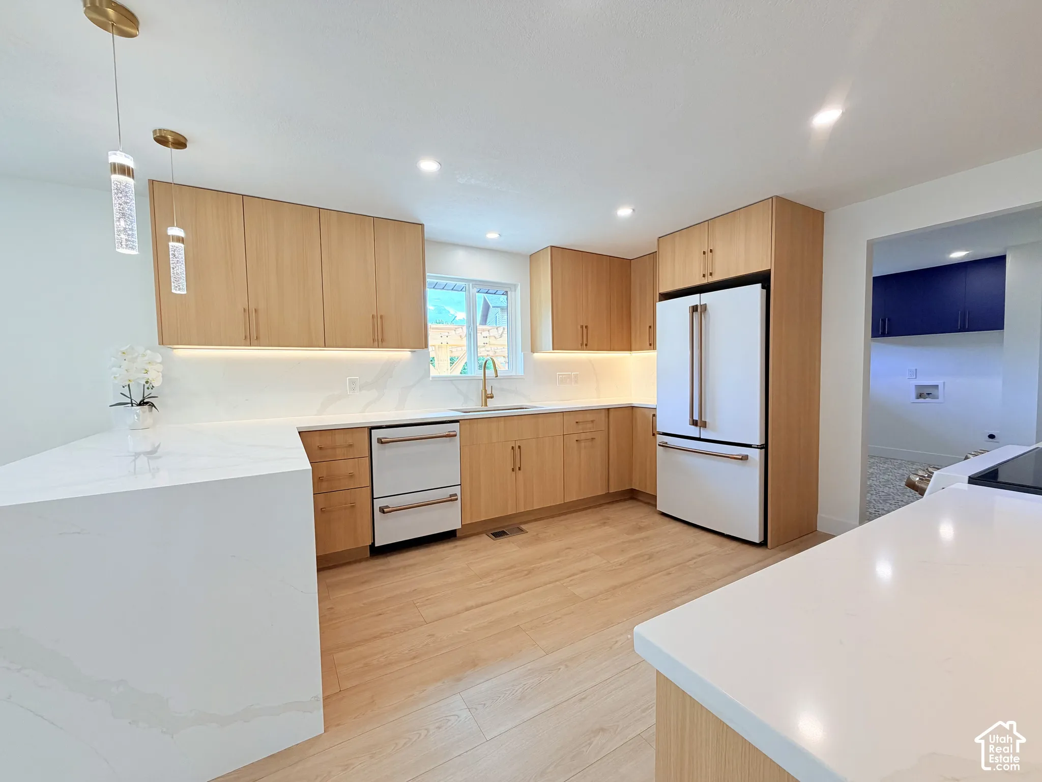 Light wood-finish cabinetry with gold-tone hardware, white quartz countertops, wood-finish flooring, and recessed lighting