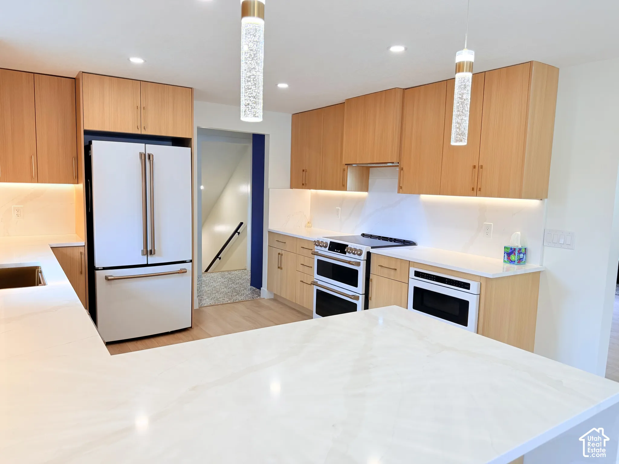 Kitchen featuring light wood cabinetry, light countertops, integrated appliances, and recessed lighting