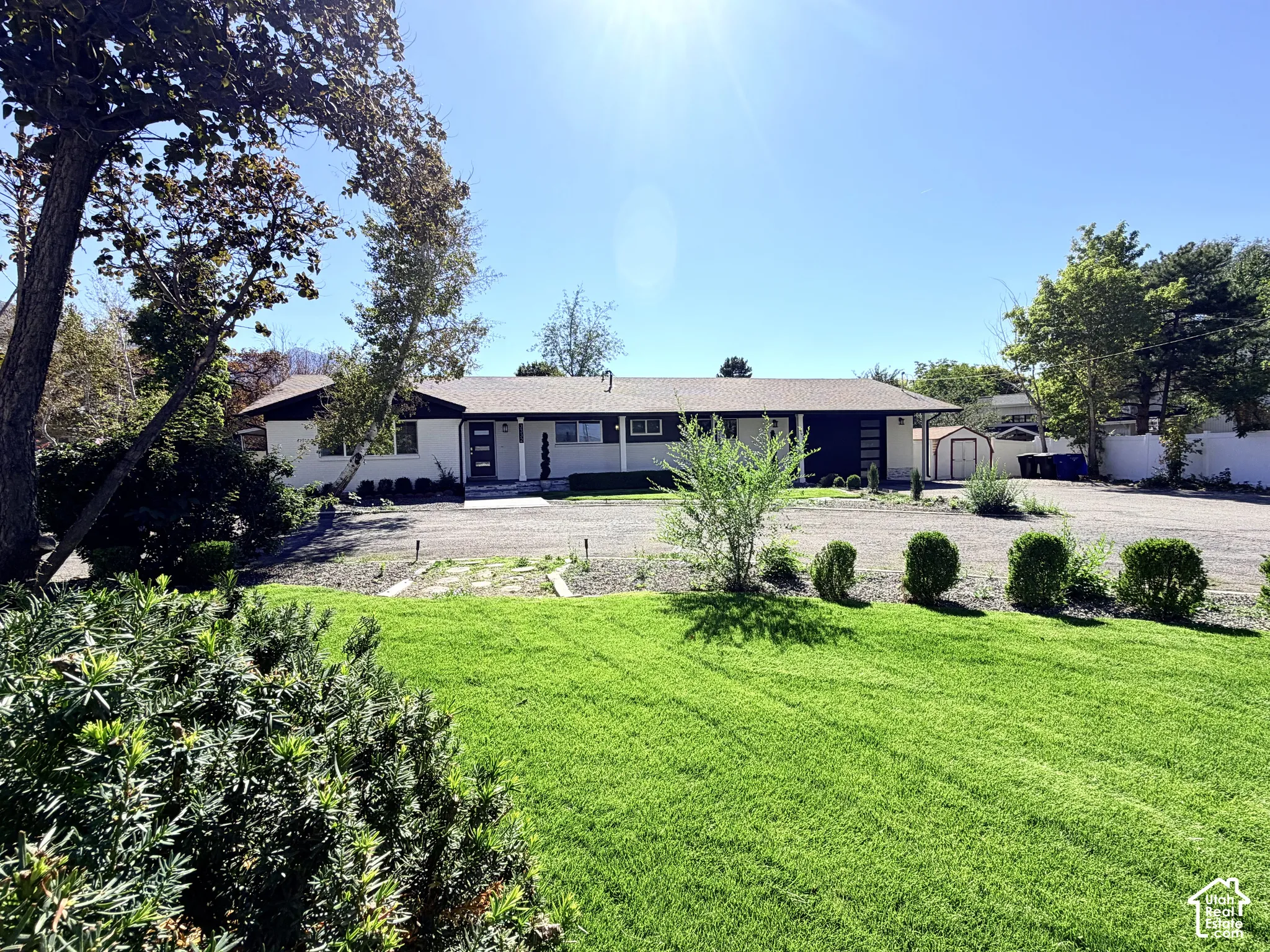 Expansive front yard featuring a manicured lawn, established trees, and mature landscaping