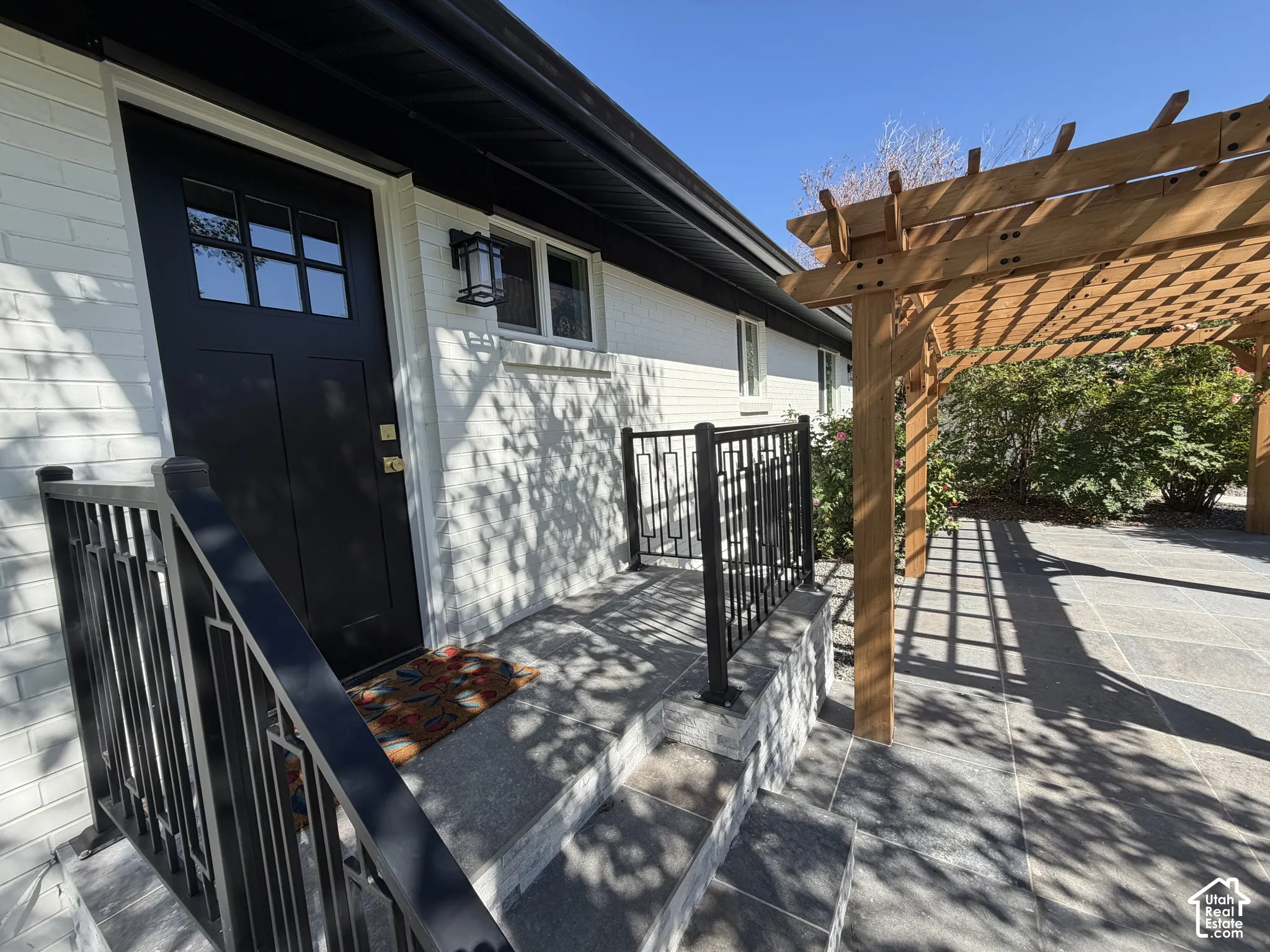 Entry featuring a black paneled door with glass inserts, a black exterior light fixture, and white brick siding