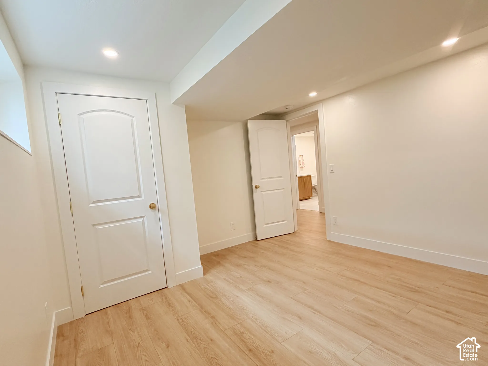 Recessed lighting, wood-finish flooring, white trim, and solid core doors