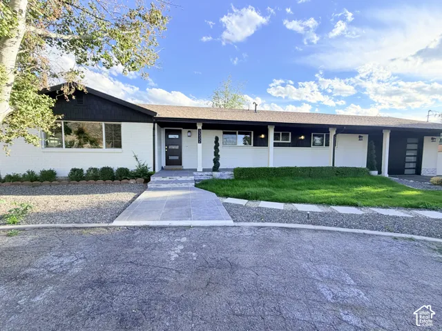 Contemporary exterior featuring a black modern entry door, white brick facade, dark trim, and a concrete paver walkway