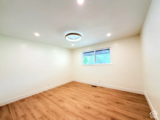 Recessed ceiling lighting, wood-finish flooring, white trim, and a window for natural illumination