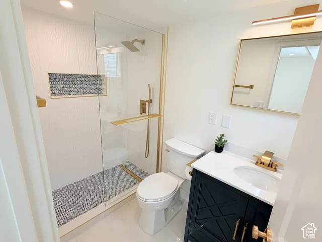 Frameless glass shower enclosure with mosaic tile, recessed shower niche, and gold-finish fixtures