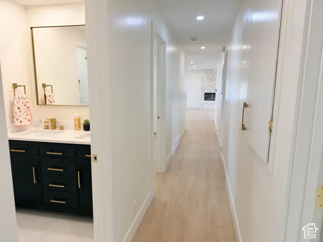 Hallway with wood-finish flooring leading to a living area with a stone-clad fireplace