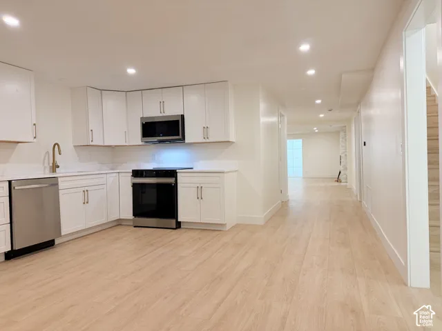 Kitchen featuring white cabinetry, stainless steel appliances, a gold-finish faucet, white countertops, and recessed lighting