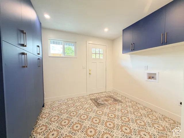 Patterned tile flooring, expansive floor-to-ceiling cabinetry, additional wall-mounted storage, a multi-pane window, and recessed lighting