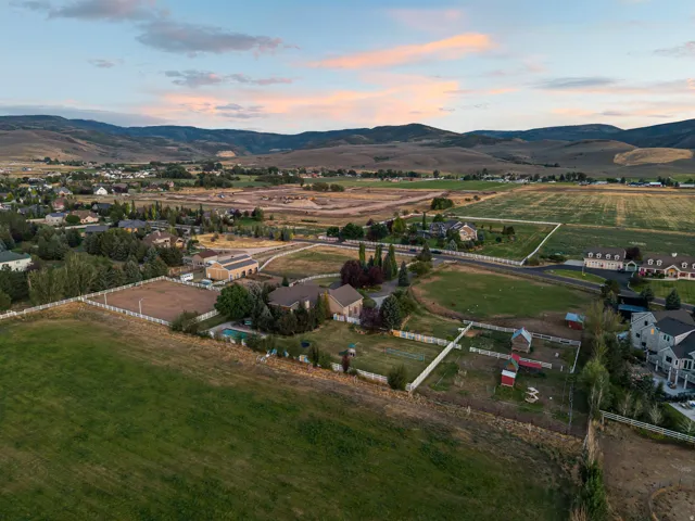 Expansive property featuring an in-ground pool, multiple fenced areas, and distant mountain backdrops
