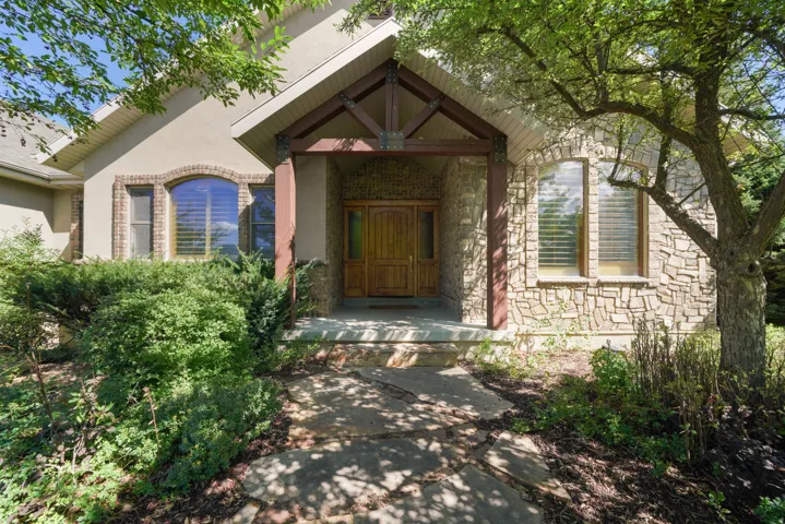 Stone and stucco exterior with arched windows, a covered entry, and a double wooden door