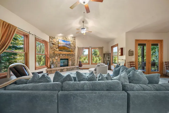 Spacious living area featuring a vaulted ceiling, recessed lighting, and exposed beam ceiling fans