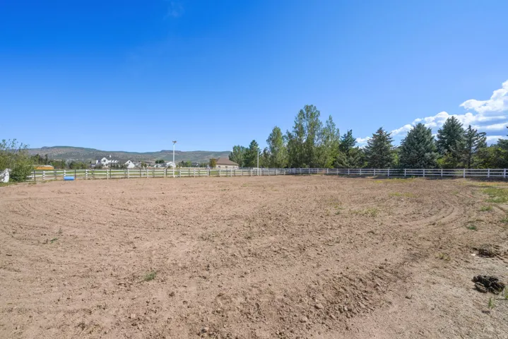 Expansive land parcel with surrounding white fencing and distant mountain scenery
