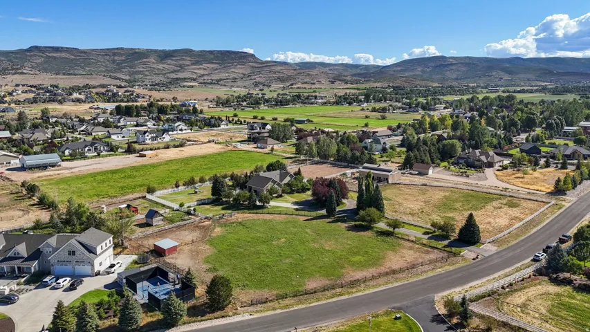 Expansive property featuring varied terrain, scattered residential structures, and distant mountainous scenery under a clear sky