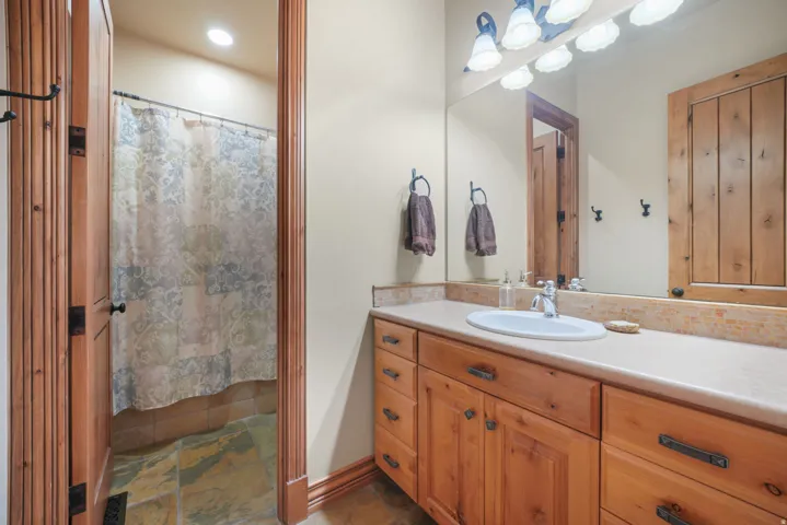 Bathroom featuring a vanity with an integrated sink, a full-width mirror, and wood-finish cabinetry