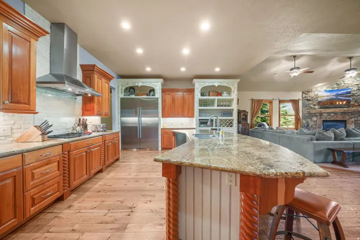 Gourmet kitchen featuring wood-finish flooring, custom cabinetry, stainless steel appliances, and granite countertops