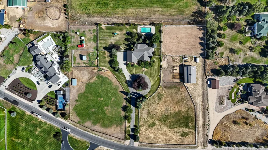 Expansive property featuring a main residence, a detached auxiliary building, multiple outbuildings, an in-ground swimming pool, and a circular driveway