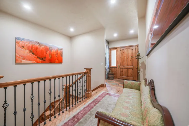 Hardwood staircase with wrought iron balusters, recessed lighting, solid wood entry door with sidelight, and wood-finish flooring in the entryway