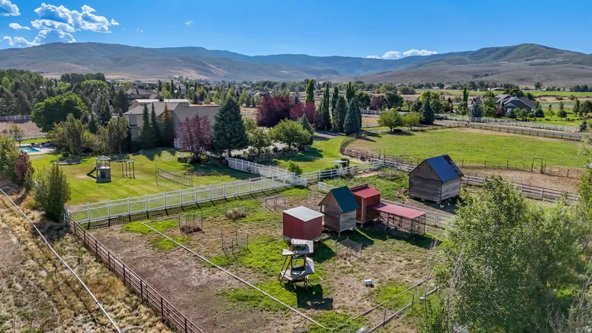 Expansive property featuring a residence, detached outbuildings, fenced pasture areas, and a pool