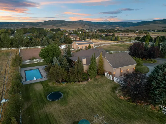 Expansive property featuring a rectangular swimming pool, diving board, substantial lawn area, and mature trees